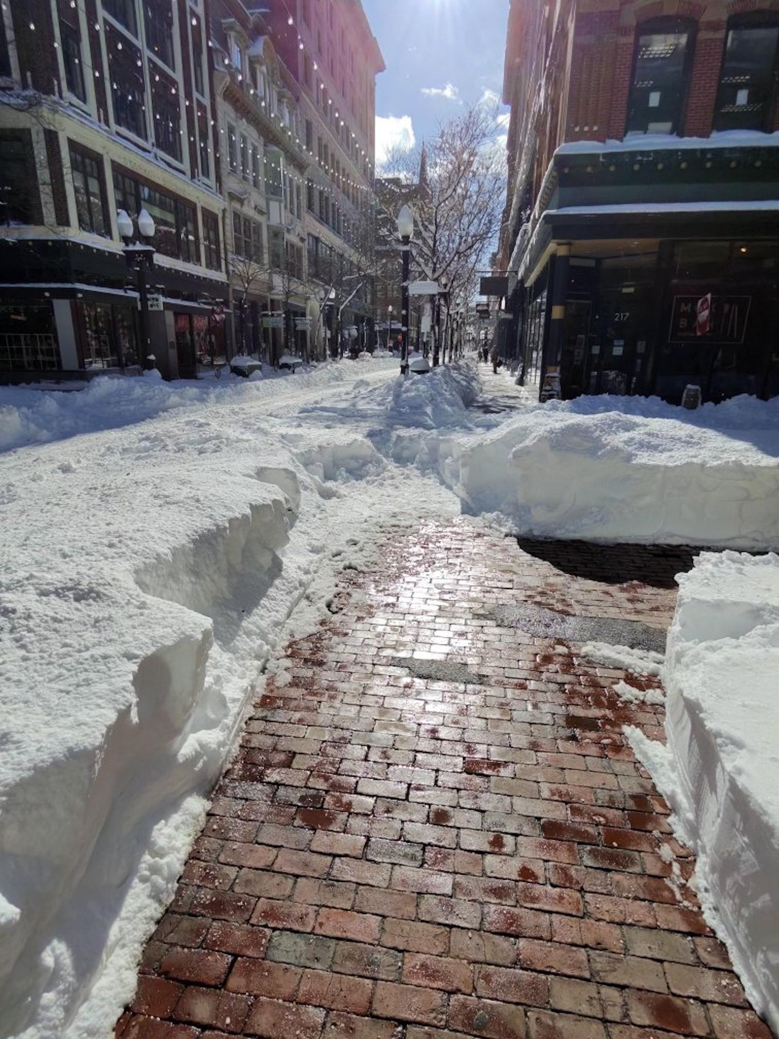 Westminster Street Providence after historic blizzard 2026 - narrow wet brick path between towering walls of snow